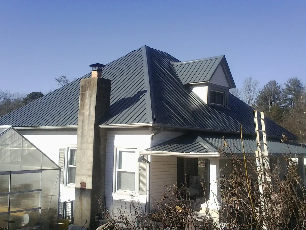 Dark blue standing seam metal roof on a white farmhouse with dormer — Slate & Tile Roof Repair by Roofing Brothers in Radnor