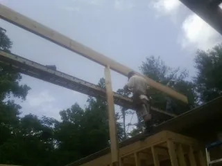 Carpenter setting a ridge beam over a new addition frame in Radnor
