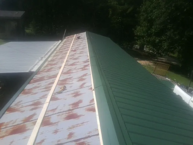 Old rusted panels beside newly installed green metal roofing — Wind Damage Roof Repair by Roofing Brothers in Radnor