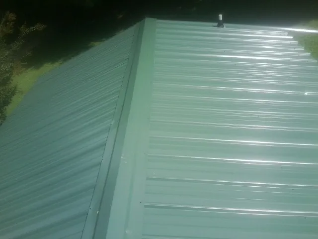 New green metal panels meeting at the ridge of a roof — Flat Roof Repair work by our crew in Radnor