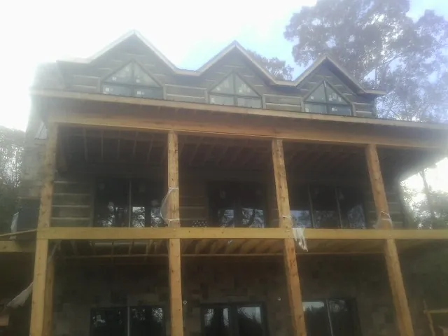 Dormers and porch framing on a large log home under construction — Roof Coating work by our crew in Radnor