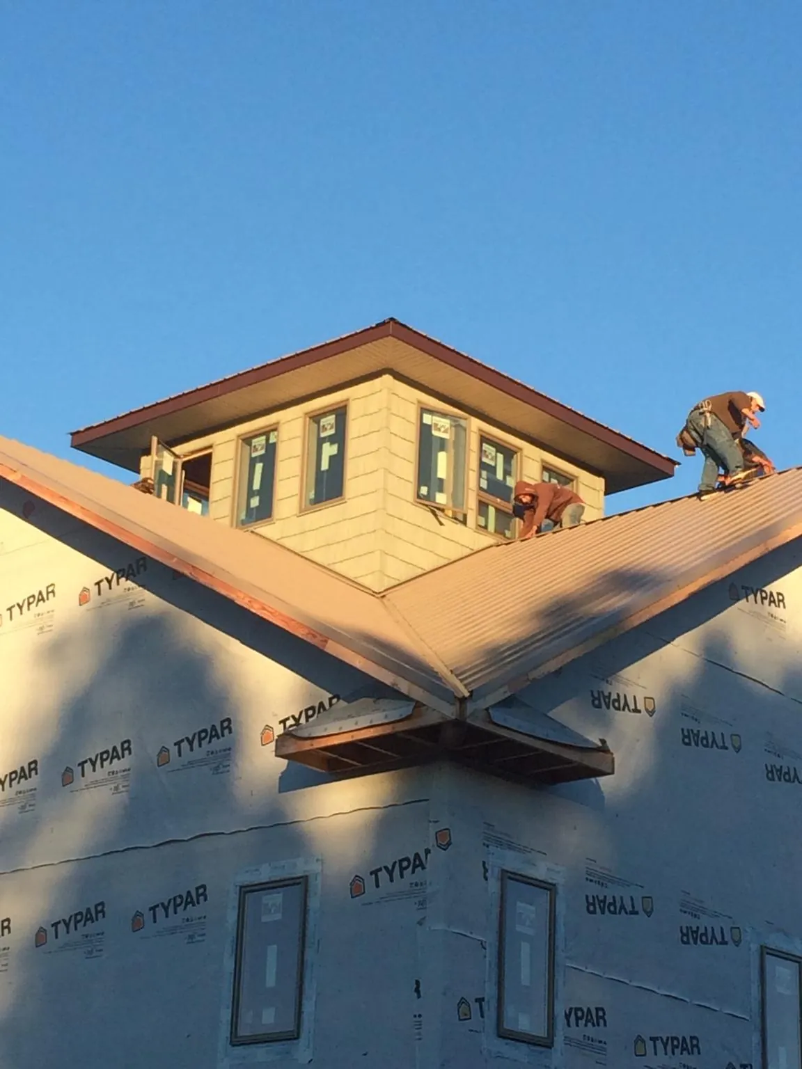 Roofers working around a rooftop cupola on a new metal roof at sunset — Roof Waterproofing in Radnor by Roofing Brothers